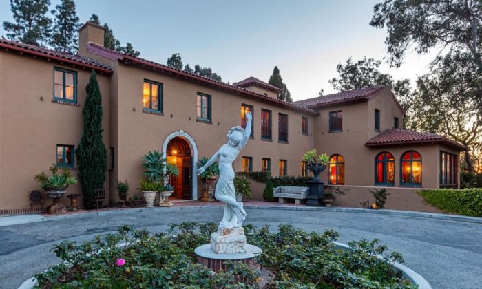 Estate at sunset with circular driveway and white statuary of  Greek female figure