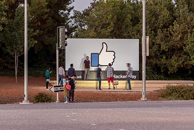 People standing in front of Facebook headquarters sign