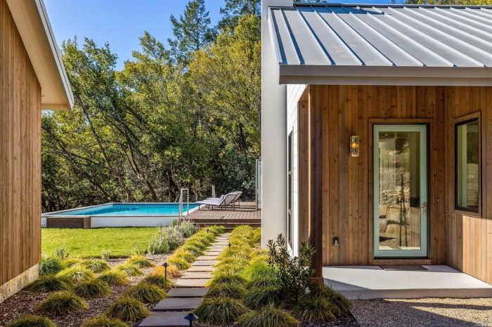 Exterior of home with door and steel roof with swimming pool in the background