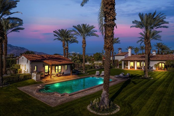 After sunset palm trees swimming pool Spanish Style home in background