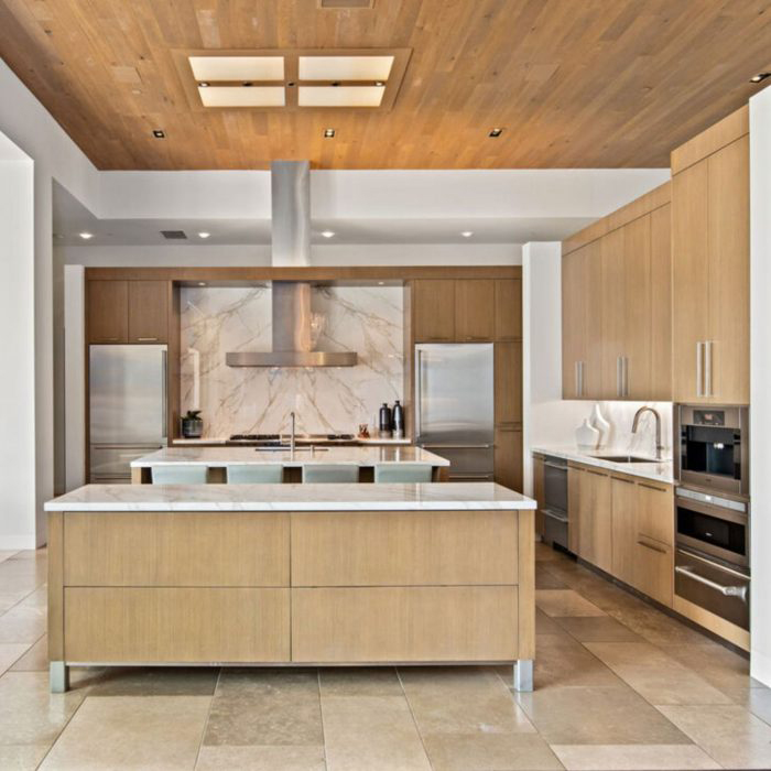 Kitchen with light wood panels and white marble backsplash