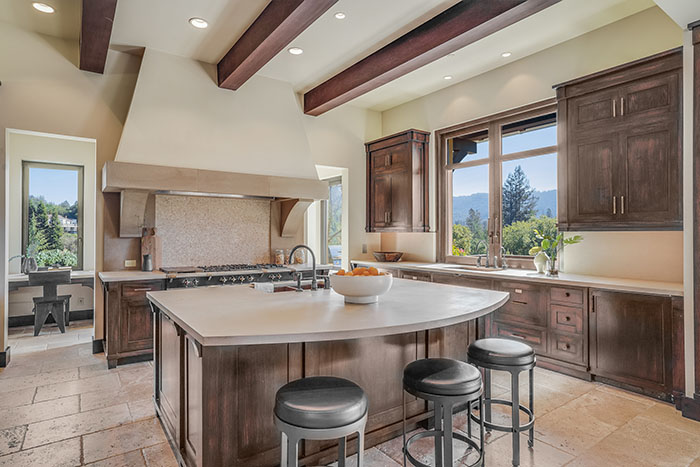 Chefs kitchen with expansive island, beamed ceilings, laCanche range in Central Portola estate