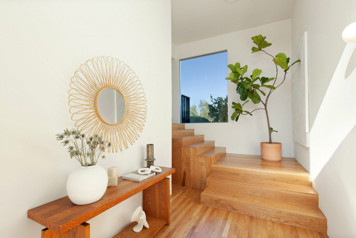 Entryway with white walls wood floor stairs fig tree sunburst design mirror