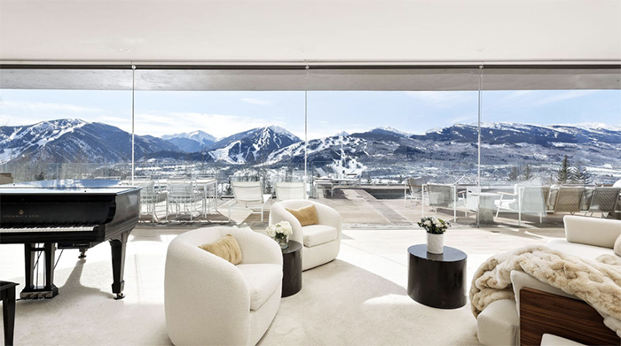 Interior with cream colored furnishings black piano plate glass vista of mountain range