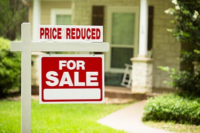 A home for-sale sign with a price reduction