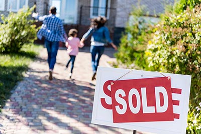 Family walking into house behind sold sign