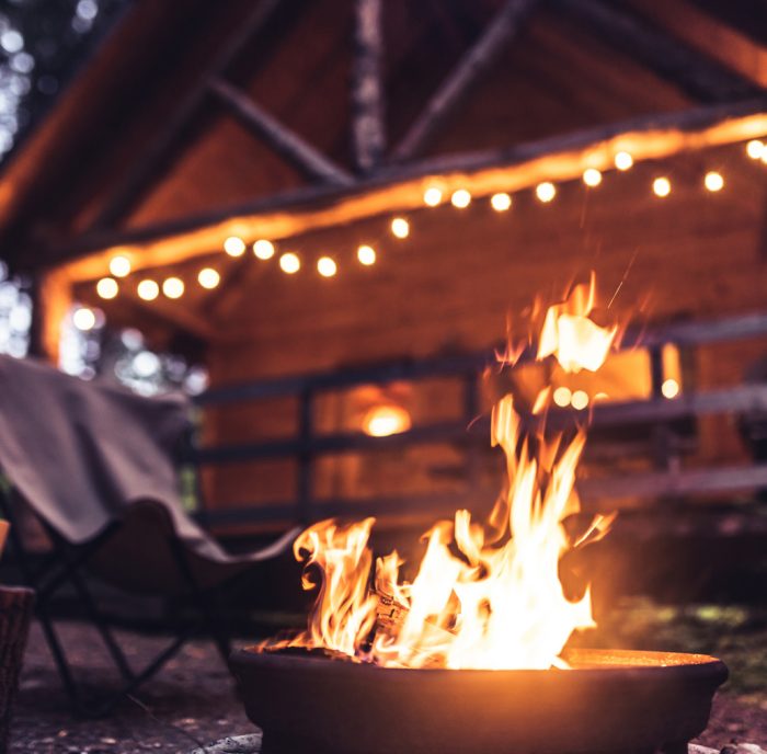 Late evening campfire in front of a wood log cabin