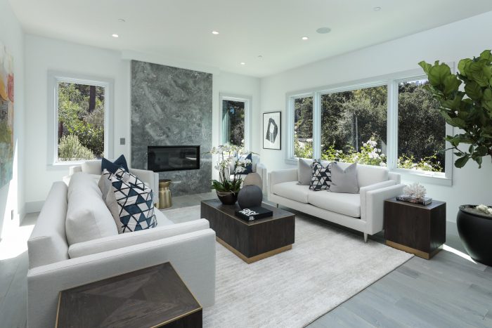 Smallish gathering room with white sofas, and a fireplace.